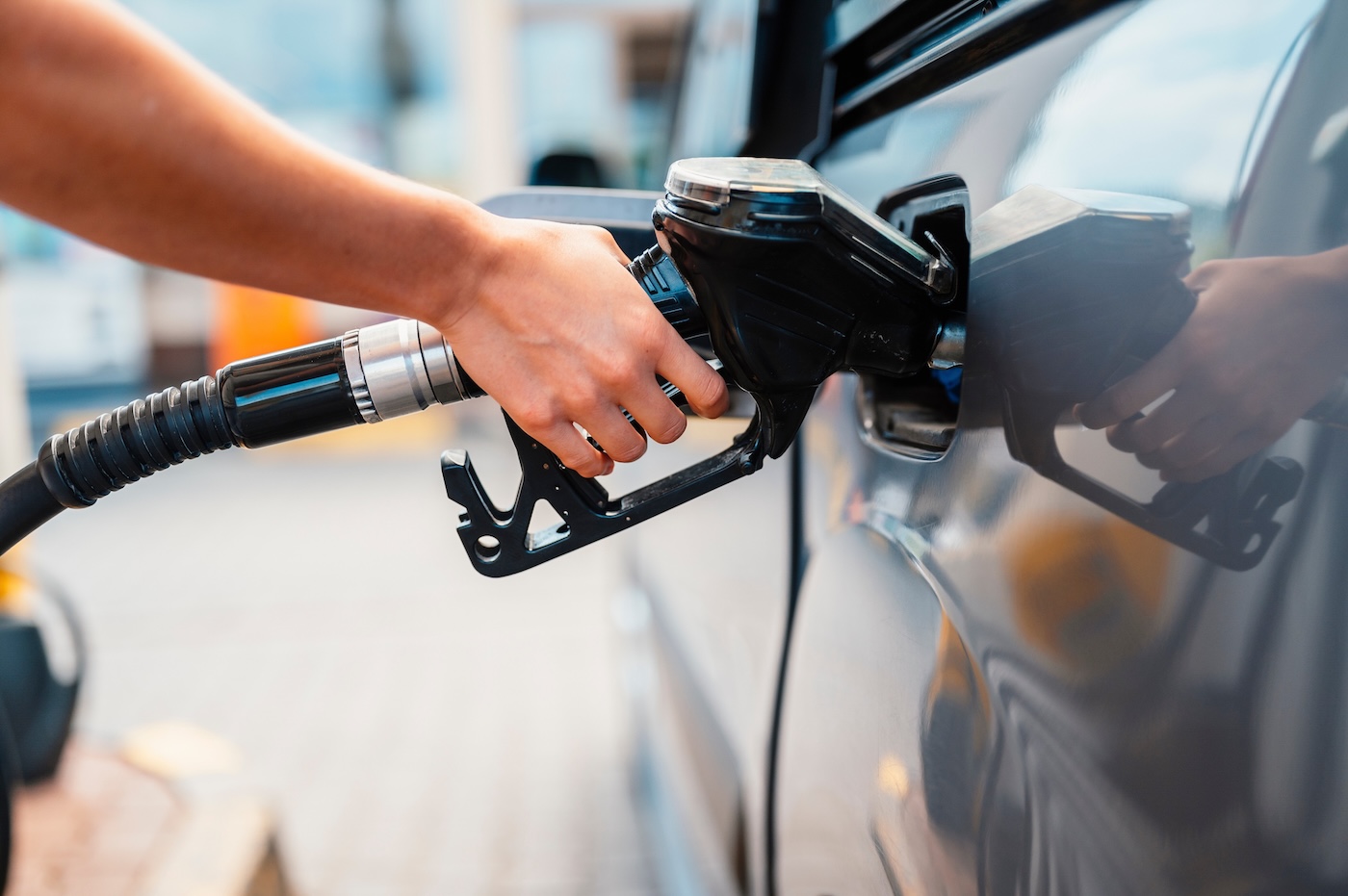 Closeup of woman pumping gasoline fuel in car at gas station.