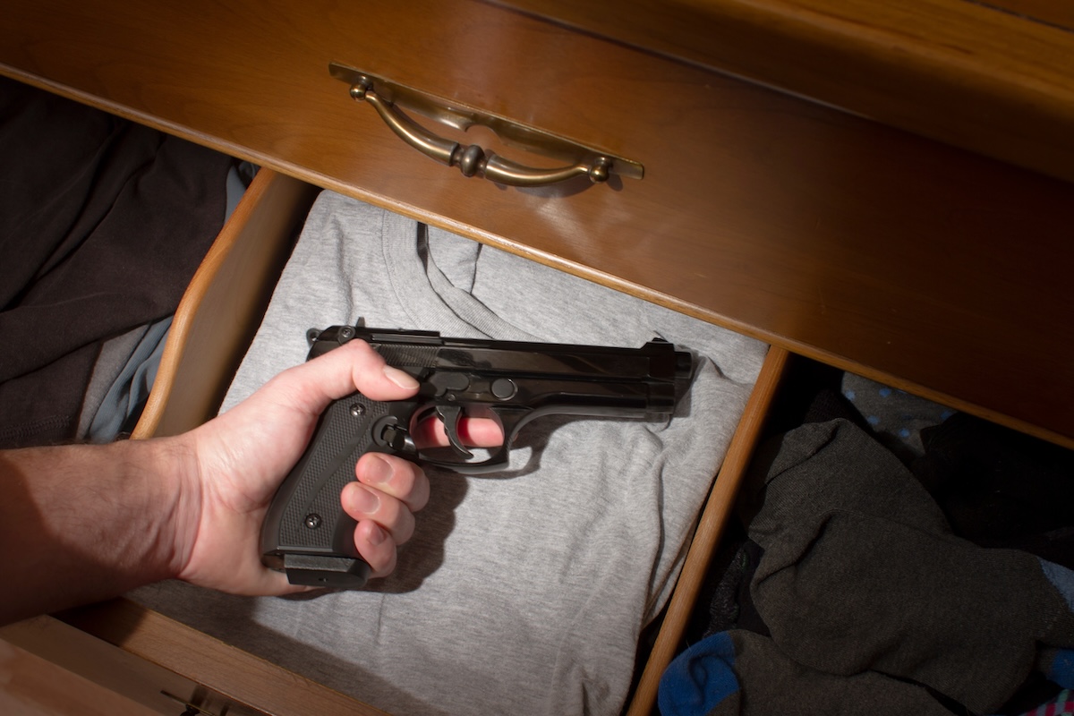hand reaching for hand gun in a drawer