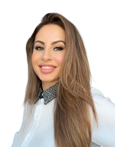 A woman with long light brown hair, wearing a white blouse with a patterned black collar, smiles at the camera against a plain light background.